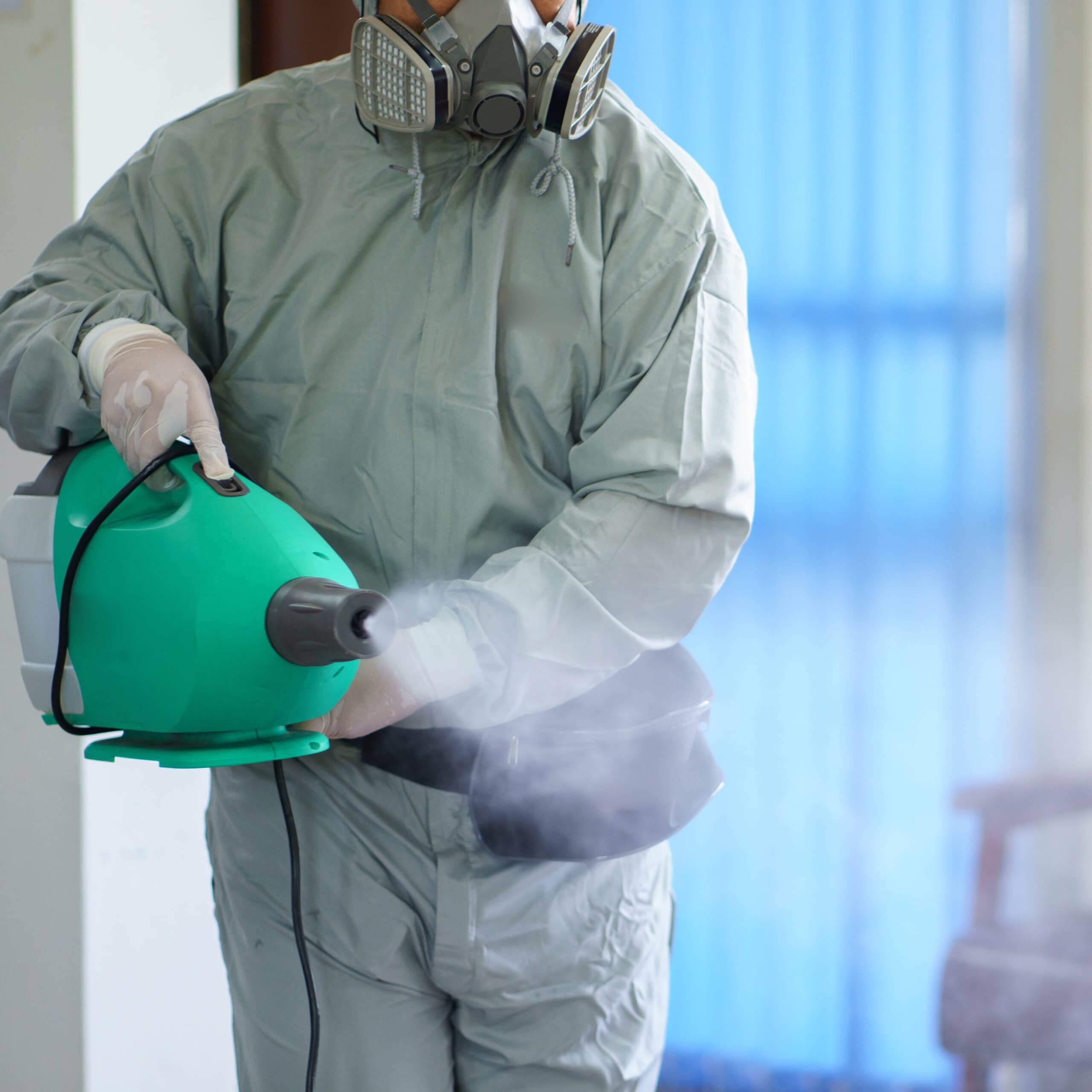 Pest controller in hazmat suit using insecticide